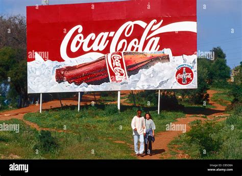 Un par camina más allá de un banner de publicidad de Coca-Cola en Argel ...