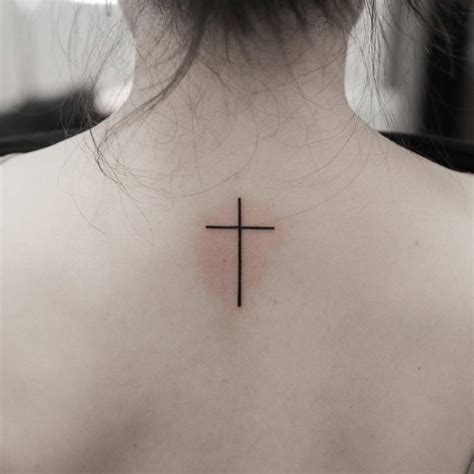 Minimalistic style cross tattooed on the upper back.