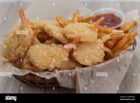 Basket of deep fried crispy shrimp served with french fries and a ...