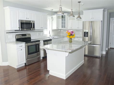 Gorgeous modern kitchen with white cabinets, stainless steel appliances, stainless pendant ...