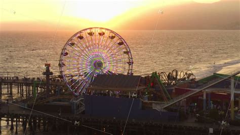 AERIAL: Close up view of Santa Monica Pier Ferris Wheel, Los Angeles at beautiful Sunset with ...