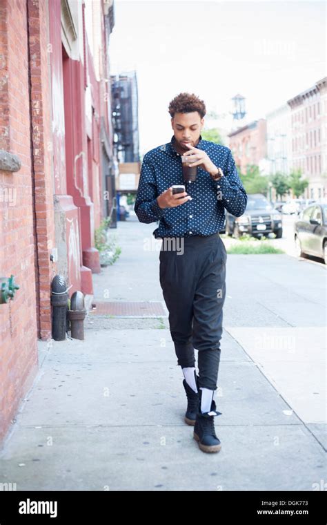 Young man walking down street with cellphone and drink Stock Photo ...