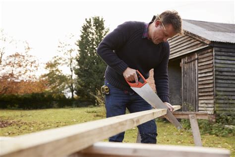 man-sawing-wood-shed | Garden Power Tools