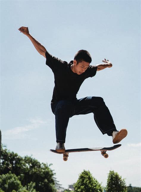 Confident young man performing high jump on skateboard on sunny day ...