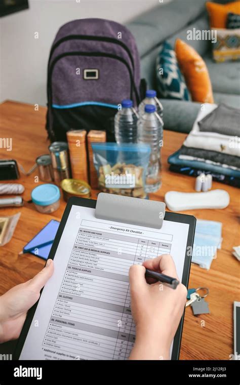 Woman doing checklist of emergency backpack Stock Photo - Alamy