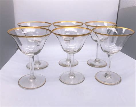 six wine glasses with gold rims on white background