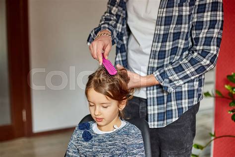 Father combing, brushing his daughter's hair at home | Stock image | Colourbox