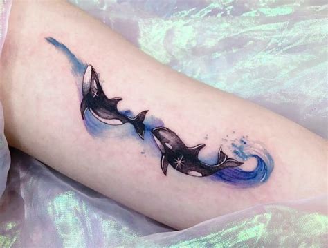 a tattoo on the leg of a woman with two dolphins in blue and black ink