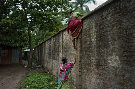 Two Bangladeshi women cross the border wall between India and Bangladesh at Hili, West Bengal ...