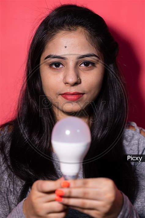 Image of Pretty young woman holding a luminous led light bulb. Green energy , saving of energy ...