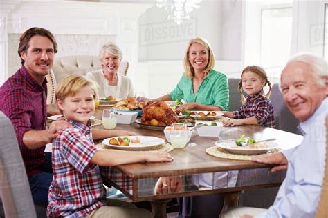 Extended Family Group Sit Around Table Eating Meal At Home - Stock Photo - Dissolve