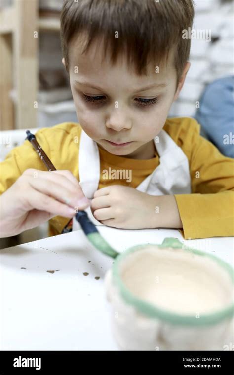 Child paints clay pot in pottery workshop Stock Photo - Alamy