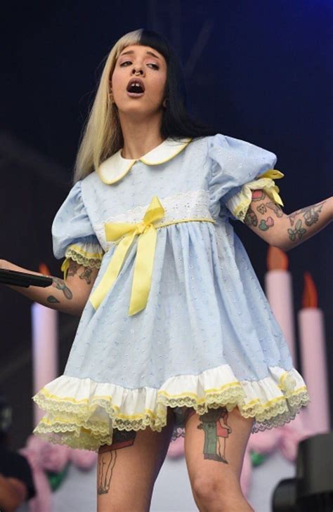 a woman in a blue dress on stage with her hands out to the side while ...