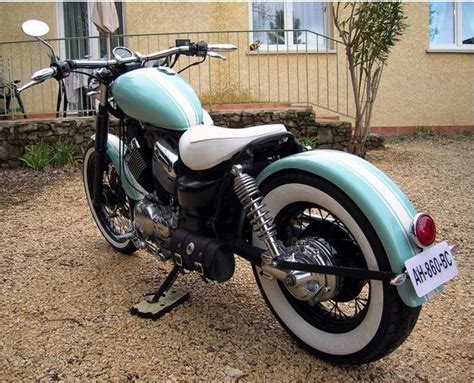 a blue and white motorcycle parked in front of a building with a tag on it's handlebars