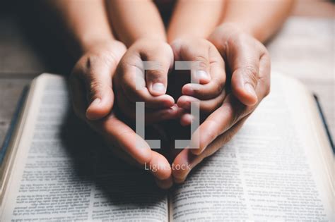 Family praying on bible — Photo — Lightstock