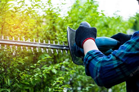 Premium Photo | Gardener holding electric hedge trimmer to cut the treetop in garden