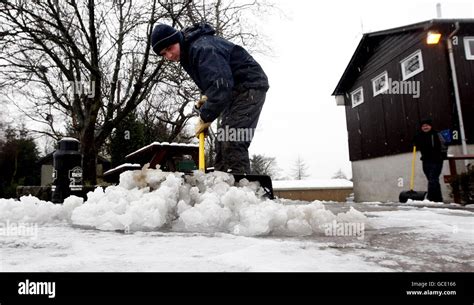 A man clears snow at Lenzie Golf Club in Scotland following fresh snow falls over night Stock ...