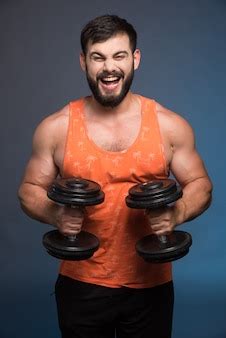 Free Photo | Strong man holding a dumbbell on dark blue wall.