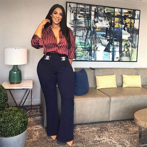 a woman standing in front of a couch with her hands on her hips and smiling at the camera