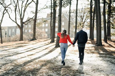 People Couple Holding Hands While Walking Near Brown Trees During Daytime Person Image Free Photo