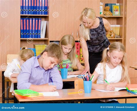 Young Teacher Helps Students Of Primary School In The Exam Stock Photo ...