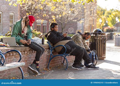 A Group of Poor People Living on Streets are Sitting on a Bench with Their Goods in Backpacks ...