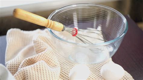 Food cooking equipment. Whisk in glas bowl. Closeup. Ingredients for cake baking. Eggs on ...