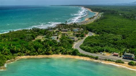 Waves rolling in toward a tree-lined beach in Loiza, Puerto Rico Aerial Stock Photo AX102_019 ...