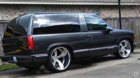 the black truck is parked on the side of the road in front of a house