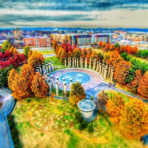 an aerial view of a park with trees in the foreground and buildings in ...