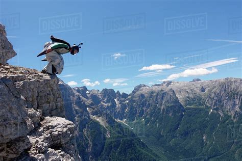 Wingsuit BASE jumper getting ready to jump from cliff, Italian Alps ...