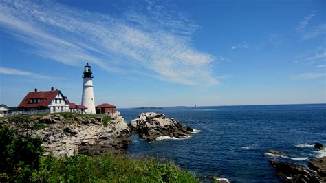 a light house sitting on top of a rocky cliff next to the ocean under a ...