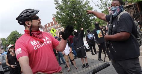 Video shows armed protesters blocking path of man in MAGA shirt