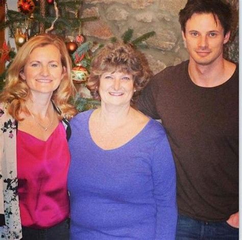 three people standing next to each other in front of a christmas tree