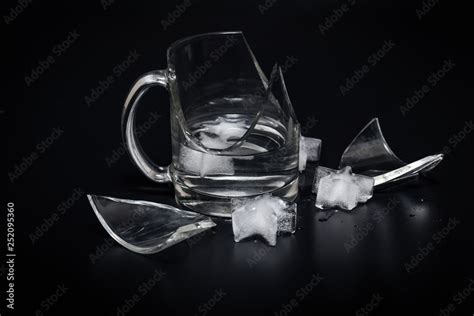 Broken glass cup with splinters, water and ice on a black background Stock Photo | Adobe Stock