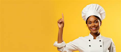 Black female chef smiling and pointing upwards wearing uniform ...