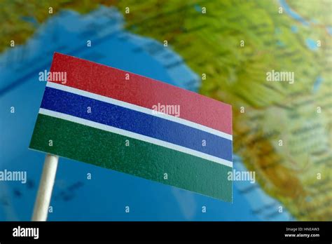 Gambian flag with a globe map as a background macro Stock Photo - Alamy