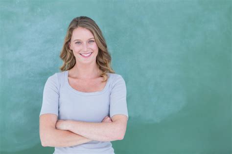 Smiling teacher standing in front of blackboard in classroom - Transcript Maker