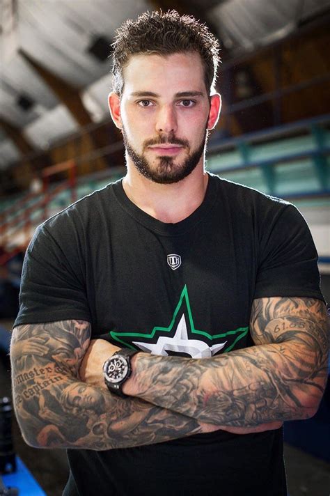 a man with his arms crossed wearing a black t - shirt and green star tattoo