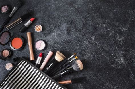 Premium Photo | Makeup products and striped cosmetic bag on dusty dark background | Trucco