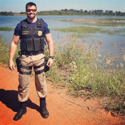 a man standing in front of a body of water wearing a police uniform and sunglasses