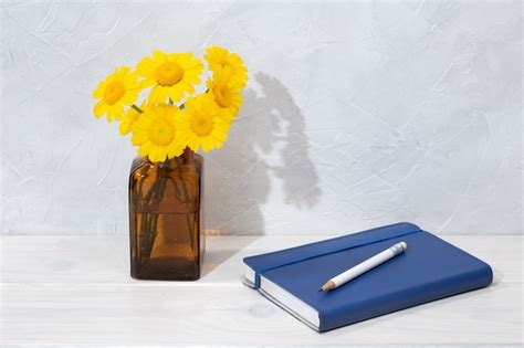 Premium Photo | Beautiful flowers in bottle and blue diary on wooden ...