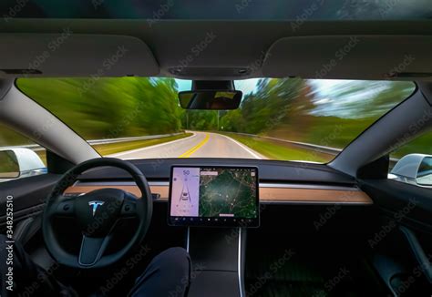 Person driving a new Tesla Model 3 on autopilot Stock Photo | Adobe Stock