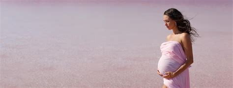 Premium Photo | Pregnant woman stands on sea beach in summer in white light dress with fluffy