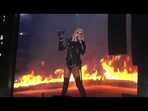 lady in black leather outfit on stage with flames behind her