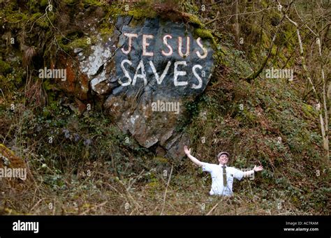 Mormon missionary posing under JESUS SAVES graffiti on exposed rock ...