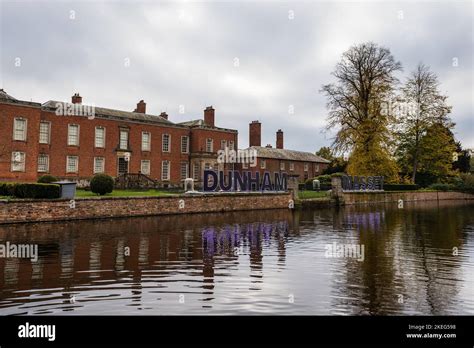 Dunham Massey Hall and Gardens reflecting in the lake with an illuminated sign ready for the ...