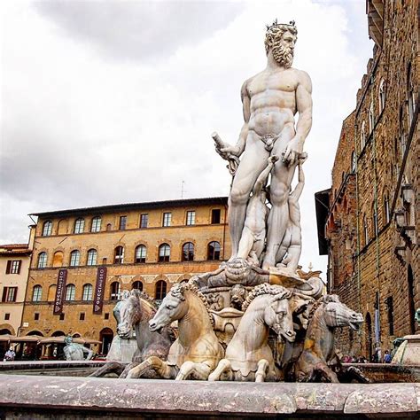 a statue in the middle of a fountain with horses around it