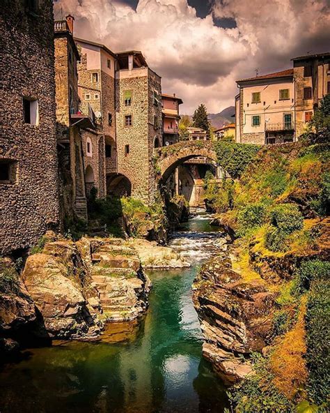 a river running through a lush green hillside next to tall buildings ...