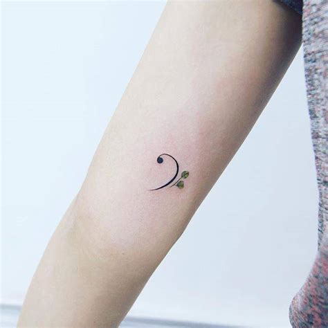 Bass clef tattoo on the right inner arm.